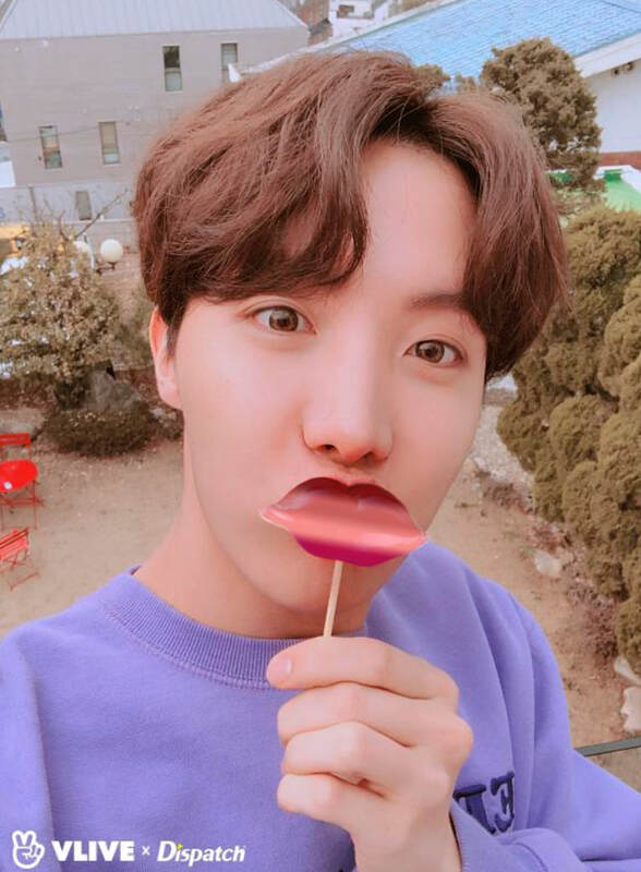 hoseok holding a blurred asexual flag lip shaped sucker against his own lips