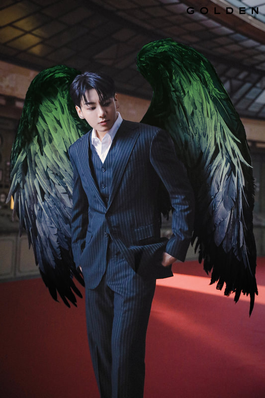 Jungkook from the Standing Next To You music video shoot in a suit with dark blurred aromantic flag colored feathered wings on his black. 