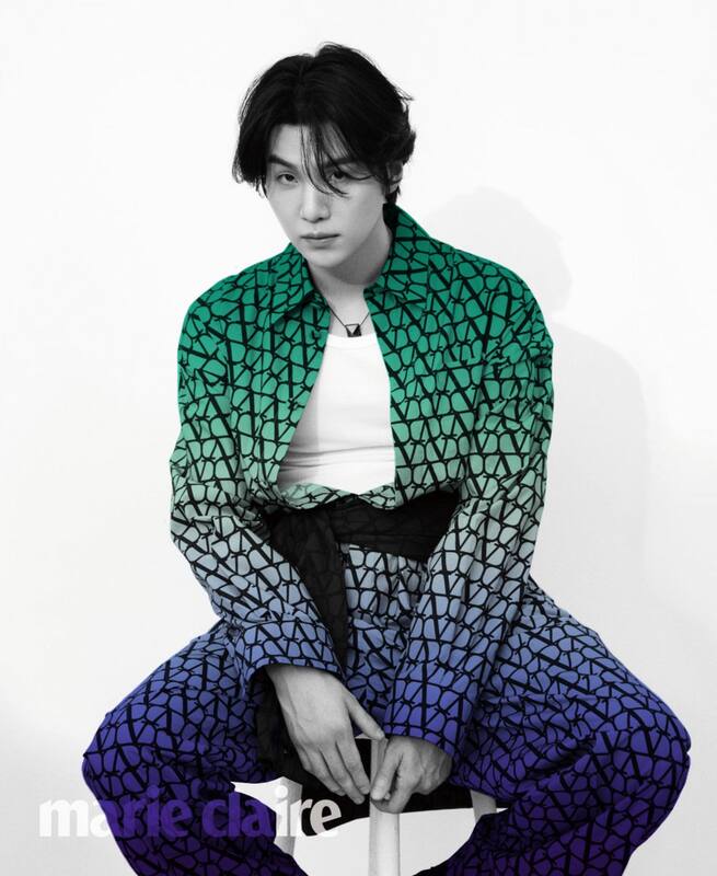 black and white marie claire image of yoongi in matching shirt and pants, the shirt being longsleeves and unbuttoned with an undershirt showing and there being a dark fabric tied around his waist. the matching shirt and pants are blurred ocean gay flag colored.